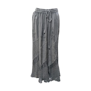 May include: Grey wide-leg trousers with a drawstring waist and embroidered floral details. The trousers have a layered, ruffled hem.