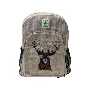 May include: A beige hemp backpack with a deer head embroidered on the front pocket. The bag has a herringbone pattern and side pockets with colourful stripes. The text "PURE HEMP" and a leaf logo are visible.