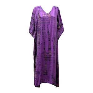 Può includere: Un lungo abito caftano viola con scollo a V. L'abito presenta un motivo tie-dye nelle tonalità del viola e del nero. Il tessuto appare morbido e leggero, adatto ai climi caldi. L'abito è lungo circa 150 cm.