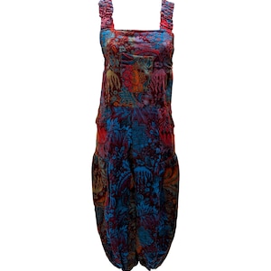May include: A vibrant jumpsuit with a floral design in blue, red, orange, and purple hues. It has a square neckline, gathered straps, and a distinctive, voluminous shape. The material seems to be a soft velvet, perfect for a unique look.