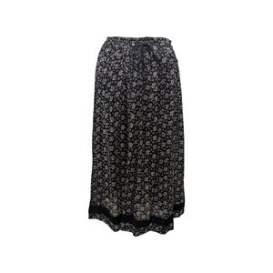 Puede incluir: Una falda maxi negra con estampado floral blanco. La falda tiene una cintura con cordón y un ribete negro en el dobladillo.
