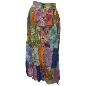 Puede incluir: Una falda larga de patchwork multicolor con cierre de botones en la parte delantera. La falda está hecha de diferentes telas con estampados florales y geométricos en tonos azules, verdes, naranjas, rosas y morados.
