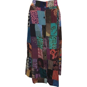 May include: A long, patchwork skirt with a button-up front. The skirt is made of various fabrics in shades of purple, blue, green, brown, and pink. The fabric has a variety of patterns, including floral, geometric, and abstract.