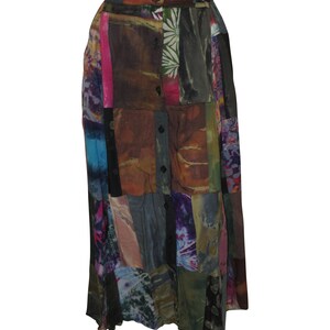 Könnte beinhalten: Ein langer Patchwork-Rock mit Knopfleiste vorne. Der Rock besteht aus verschiedenen Stoffen in Braun-, Grün-, Blau-, Lila- und Rosatönen. Der Rock hat eine hohe Taille und eine fließende Silhouette.
