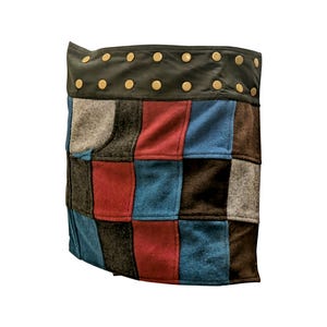 May include: A patchwork skirt with a brown leather waistband and gold studs. The skirt is made of different colored fabrics, including red, blue, and gray.