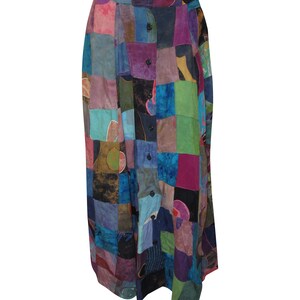 Puede incluir: Una falda larga de patchwork con cierre de botones en la parte delantera. La falda está hecha de varias telas en tonos azules, verdes, morados y marrones. La falda tiene una cintura alta y una silueta fluida.