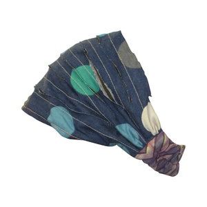 May include: A blue headband with a white and blue polka dot pattern. The headband has a frayed edge and a floral print on the inside.