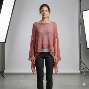 May include: A coral-colored, open-front poncho with short sleeves. The lightweight knitwear has a slightly sheer appearance and a scalloped hemline. The model is wearing a gray top and black pants.