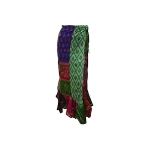 May include: A patchwork wrap skirt with panels of various patterned fabrics. The skirt incorporates floral, geometric, and ikat designs in blue, green, pink, and purple. It is tied at the waist. The skirt's design is a vibrant mix of colours and patterns.