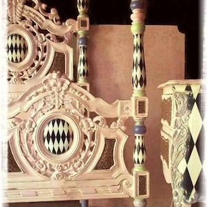 May include: Ornate, cream-colored bed frame with decorative carvings and a harlequin pattern. The bed posts are painted with black and white diamond shapes, accented with green, purple, and gold details. The headboard features a circular design with a black and white diamond pattern.