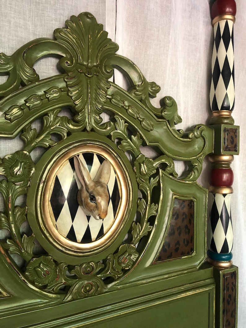 May include: A green wooden headboard with intricate carvings and a circular medallion featuring a white rabbit sculpture against a black and white checkered background.