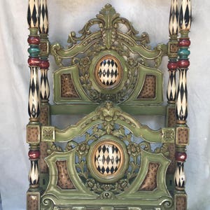 May include: Ornate, green four-poster bed frame with decorative carvings and patterned accents. The bed frame features black and white diamond patterns, red and teal accents, and leopard print details.