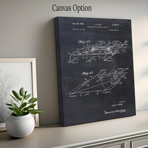 May include: A black canvas print featuring a detailed white schematic diagram of an electronic circuit. The text "Canvas Option" is at the top. The diagram includes dates, figures, and the inventor's name, Jack S. Kilby. A framed picture and a potted plant are in the background.