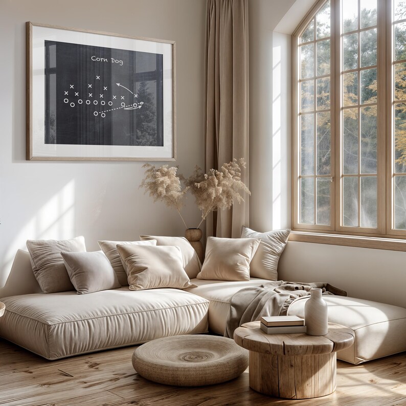 Puede incluir: Un sof&aacute; seccional beige claro con varios cojines, una mesa de caf&eacute; de madera y un jarr&oacute;n con flores secas. El sof&aacute; est&aacute; en una sala de estar con una ventana grande y una pizarra enmarcada con una jugada de f&uacute;tbol dibujada en ella. La pizarra dice "Corn Dog".