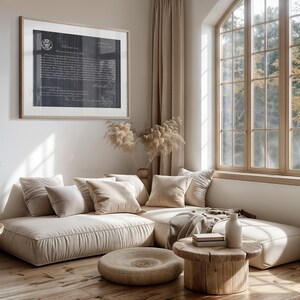 May include: A beige sectional sofa with multiple pillows, a wooden coffee table, and a vase with dried flowers in the background. The sofa is in a living room with a large window and beige curtains.