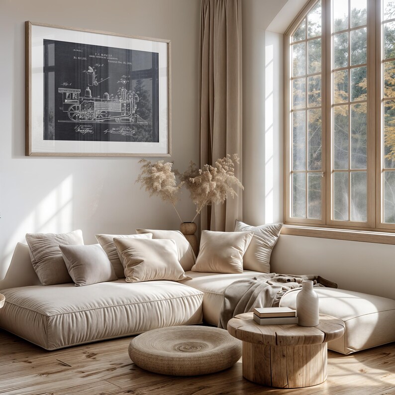 May include: A beige sectional sofa with plush cushions and a wooden coffee table. A black and white framed print of a vintage steam engine design hangs on the wall behind the sofa. The sofa is in a living room with a large window and beige curtains.