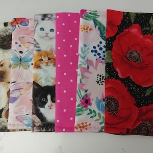 May include: Six rectangular fabric pieces arranged side-by-side. The patterns include a collage of dog faces, butterflies on a light pink background, a stack of cat faces, a bright pink fabric with white polka dots, a floral print, and large red poppies.