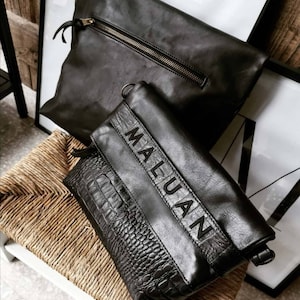 Peut inclure: Deux sacs en cuir noir. Le plus petit sac a une texture en cuir de crocodile et le texte "MALUAN" imprimé dessus.