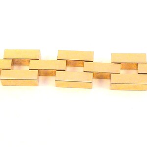 May include: A gold chain bracelet with a square link design.
