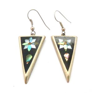 May include: A pair of silver-toned triangle earrings. Each earring has a black inlay with a flower design and iridescent accents. The earrings have a hook closure.