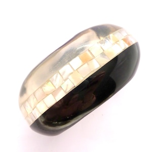 Peut inclure: Un bracelet jonc argenté avec une base noire et une bande de carreaux carrés nacrés irisés. Le bracelet a une finition lisse et polie et un design incurvé. Bijoux.