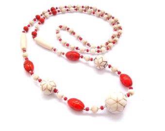 Peut inclure: Un long collier de perles blanches et rouges avec des perles blanches ornées d'une fleur sculptée.