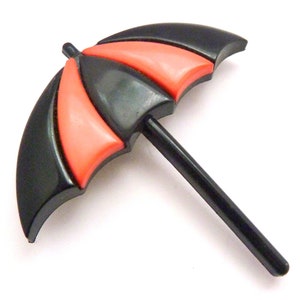 May include: A black and red plastic umbrella brooch. The umbrella is closed and has a black handle.
