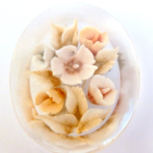 May include: A white ceramic dish with a floral design. The flowers are in shades of pink, orange, and white. The dish is decorated with gold accents.