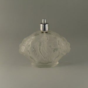 Peut inclure: Un flacon de parfum en verre givré avec un atomiseur argenté. Le flacon est décoré d'un motif en relief d'une femme et de fleurs.