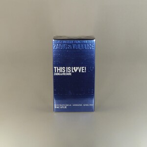 May include: A blue rectangular box of Zadig & Voltaire fragrance. The box features the text "THIS IS LOVE!" and "ZADIG & VOLTAIRE" in white. The box contains 50 ml (1.6 fl oz) of Eau de Toilette.