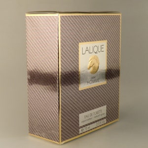 K&ouml;nnte beinhalten: Eine braune und goldene Schachtel mit einem goldenen Pferdelogo und dem Text "Lalique pour Homme" auf der Vorderseite. Die Schachtel ist mit "Eau de Toilette vaporisateur - nat&uuml;rlicher Spr&uuml;hkopf e 75 ml 2.5 fl. oz." beschriftet.