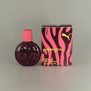 May include: A dark red perfume bottle with a pink cap next to a box with a pink and black zebra stripe design. The box has the word "ANIMAGICAL" and a yellow Puma logo. The bottle contains 20 ml or 0.67 fl oz.