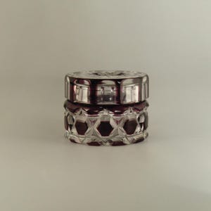 May include: A clear glass jar with a purple geometric pattern. The jar has a lid and is perfect for storing small items.