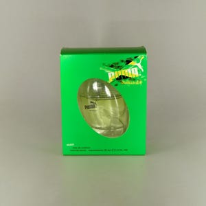 May include: A green box featuring a clear oval perfume bottle. The box displays the Puma logo and "Jamaica 2". The bottle is labelled "Puma Jamaica 2 man" and contains 30 ml of eau de toilette.
