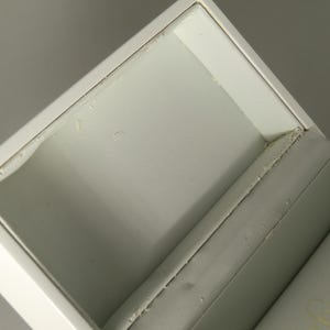 Op de afbeelding: Witte juwelendoos met een wit fluwelen interieur. De doos is open en het deksel is opengeklapt.