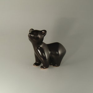 May include: A black ceramic bear figurine with a glossy finish. The bear is standing on all fours and looking up.