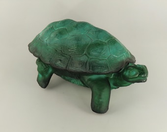 May include: A green turtle figurine with a textured shell and detailed features. The figurine is a solid color and has a glossy finish. The turtle is a decorative item.
