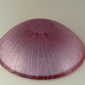 May include: A pink glass bowl with a textured, web-like design on the bottom.