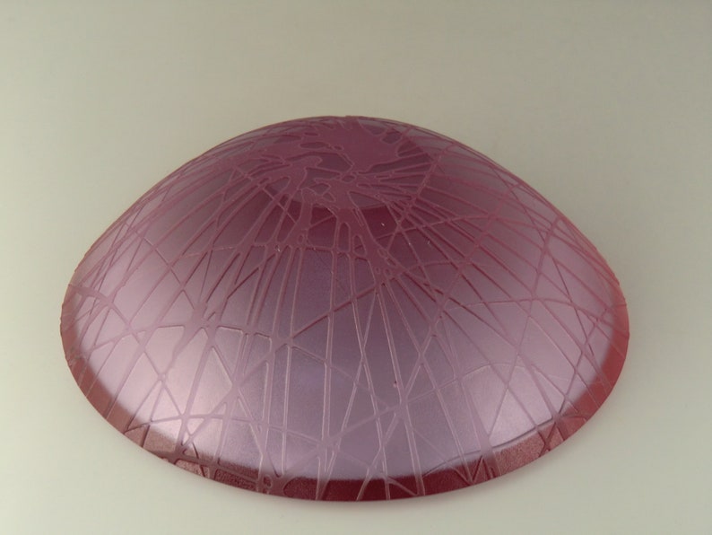 May include: A pink glass bowl with a textured, web-like design on the bottom.