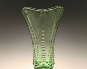 May include: A green glass vase with a fluted design and a wide, flared opening.