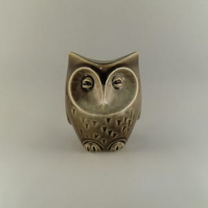 Peut inclure: Une figurine de hibou en céramique avec un glaçage brun et blanc. Le hibou a un design détaillé avec un motif texturé sur son corps.