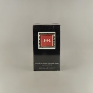 May include: A black rectangular box of J-H-L custom blended cologne spray. The box has a red square with the letters J-H-L in white. The text "3.4 FL. OZ. LIQ/100 ML" is printed on the box.