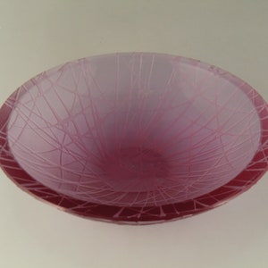 May include: A pink glass bowl with a frosted finish and a spiderweb design.