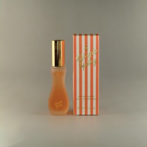 May include: A small bottle of orange-coloured perfume with a gold cap and a label that says "Gigi's Holiday". The bottle is next to a box with a striped design and the text "Gigi's Holiday Eau de Toilette Parfum Vaporisateur 30 ml 1 fl oz".