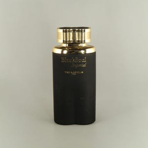 May include: A black perfume bottle with a gold cap. The bottle has gold lettering that reads "BlackSoul Imperial" and "YVES LAFELLE PARIS". The bottle is rectangular and has a matte finish.