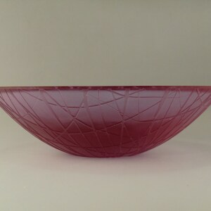 May include: A large, pink glass bowl with a textured, web-like design.
