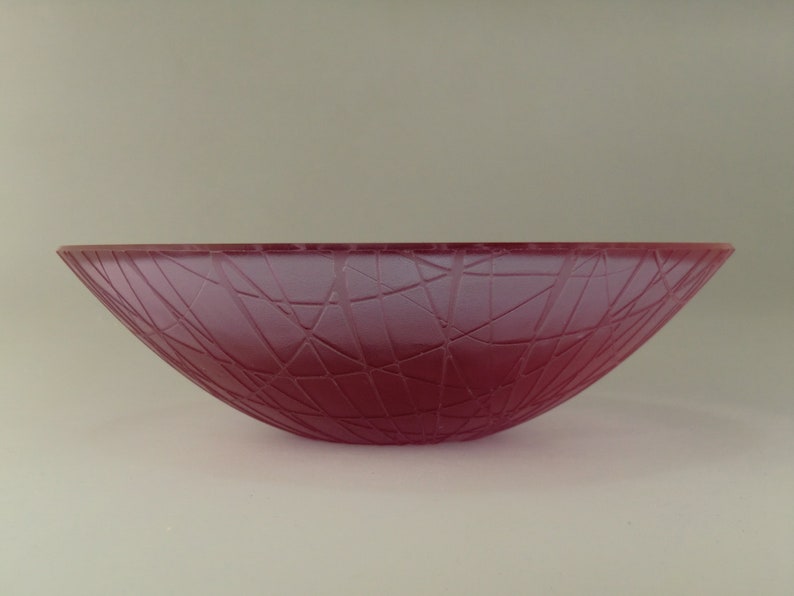May include: A large, pink glass bowl with a textured, web-like design.