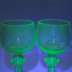 Può includere: Due bicchieri da vino in vetro verde trasparente con una coppa arrotondata e un gambo corto.