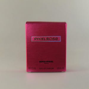 May include: A rectangular, textured, fuchsia-coloured box of Sonia Rykiel perfume. The box features the text "RYKIEL ROSE" in a rectangular label, and "SONIA RYKIEL PARIS" below. The box contains 15ml of Eau de Parfum.