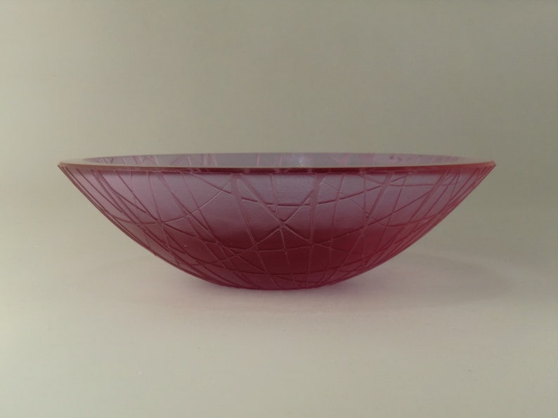 May include: A frosted glass bowl with a pink hue and a geometric pattern.